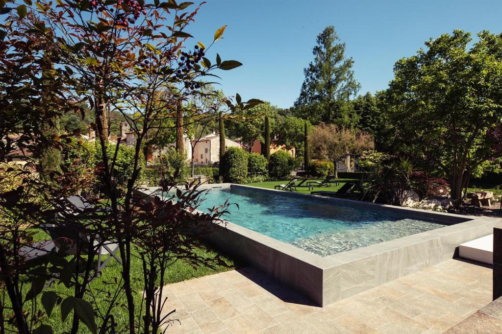 明乔河畔的瓦雷奇奥Relais Borghetto的一座树木繁茂的庭院内的游泳池