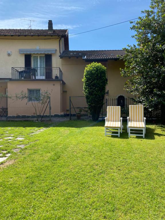 坎诺比奥Azalea Appartamenti的两把椅子坐在房子前面的院子中