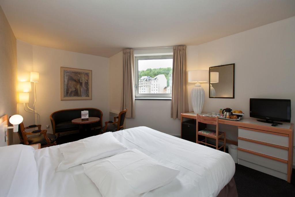 卢尔德天堂酒店的酒店客房配有一张床、一张书桌和一台电视。
