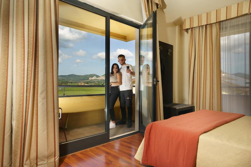 阿西西克丽斯塔罗酒店的男人和女人站在一个窗户的房间