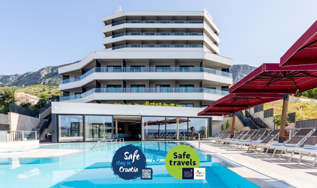 杜埃Hotel Plaža Duće的大楼前设有游泳池的酒店
