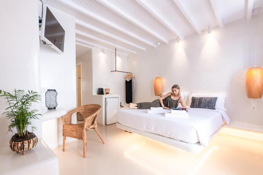 米克诺斯城Anastasia's Visage Stylish Accommodation Rooms City Centre Mykonos的坐在房间里床边的女人