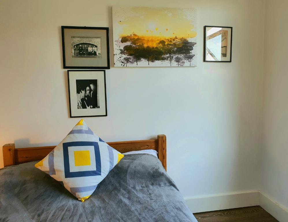 伦敦Home In Queen's Park的卧室配有一张墙上挂有照片的床