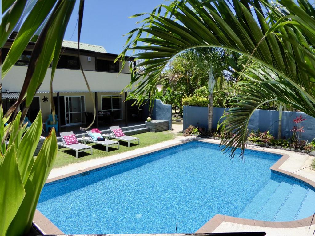 拉罗汤加Taakoka Muri Beach Villa的一个带椅子的游泳池,并种植了棕榈树