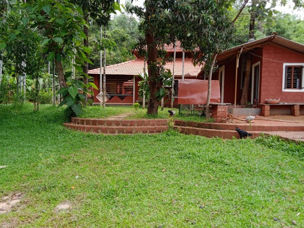 门格洛尔NIDHIVANA FARMS & RESORT, bakrebail-salethoor rd, Mangalore的院子里有树的红色小房子