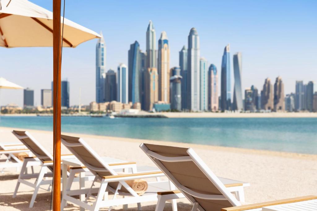 迪拜Adagio Premium The Palm的城市海滩上的一排躺椅