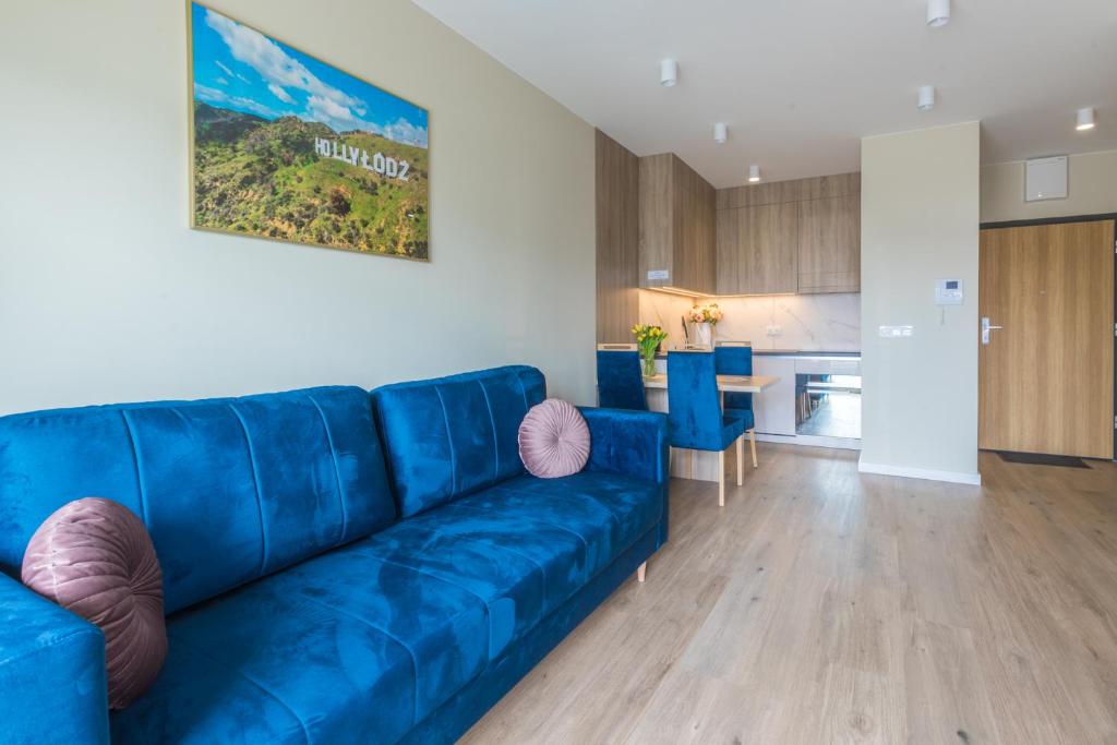 罗兹HollyŁódź Apartment NETFLIX的客厅设有蓝色沙发,配有厨房