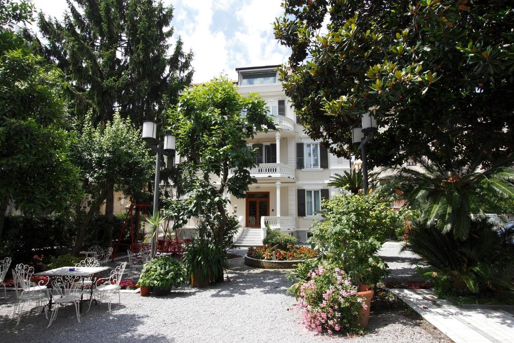 瓦拉泽Genovese Villa Elena Residence的白色的房子,配有桌椅和树木
