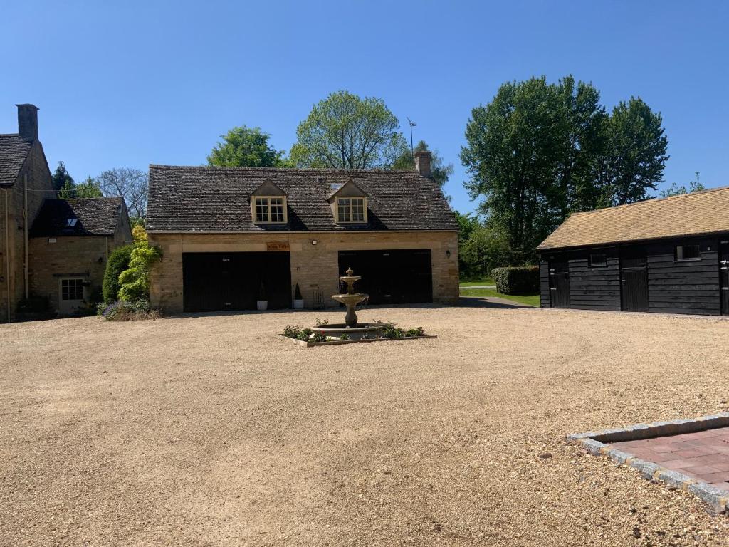 BledingtonStable Lodge at Bledington Mill的房屋前有消防栓的大院子