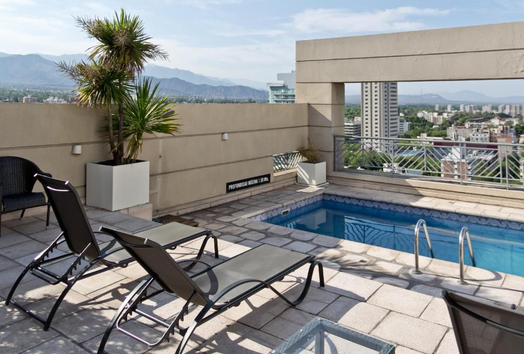 门多萨门多萨亚美利安酒店的一座带椅子的庭院和一座位于大楼内的游泳池