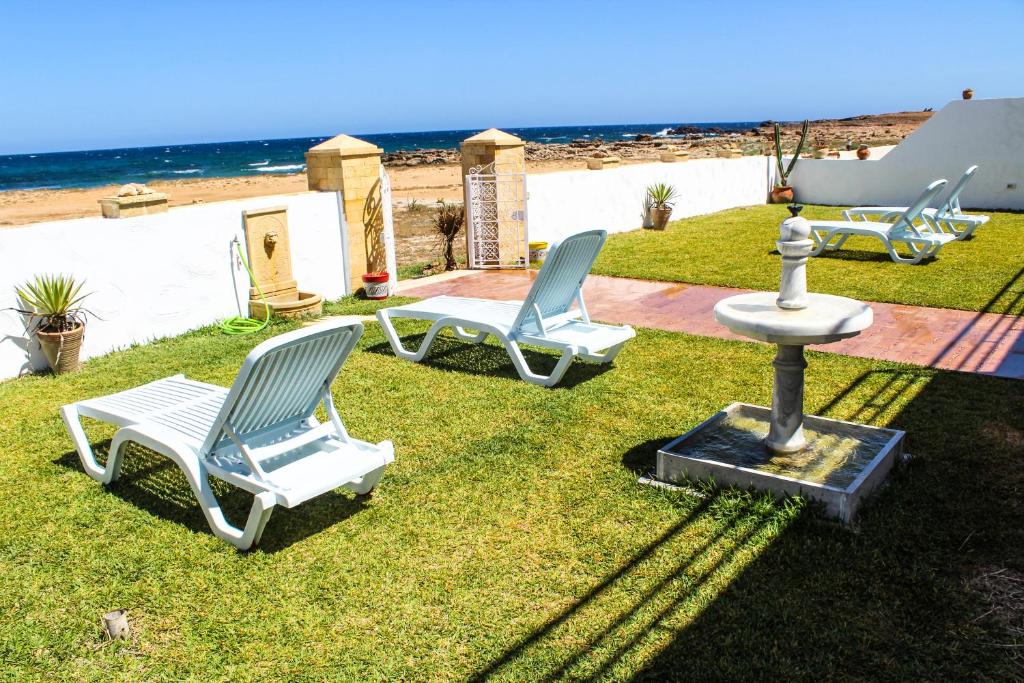 胡瓦里耶Villa Island Zembra的海滩附近的草地上设有两把椅子和一个喷泉