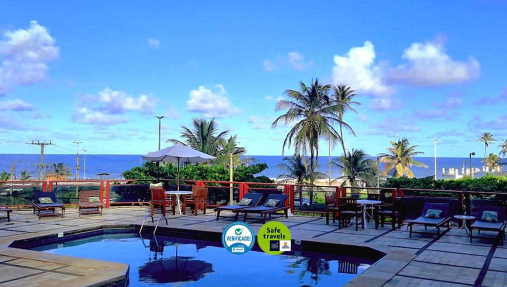 萨尔瓦多巴哈马尔酒店的一个带桌椅的游泳池以及大海