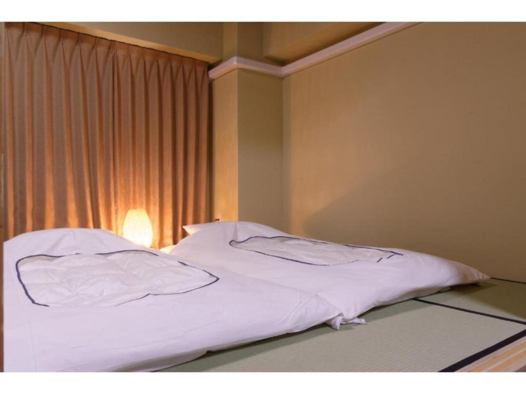 川口市WALLABY HOUSE - Vacation STAY 38653v的窗户客房内的一张带白色床单的床