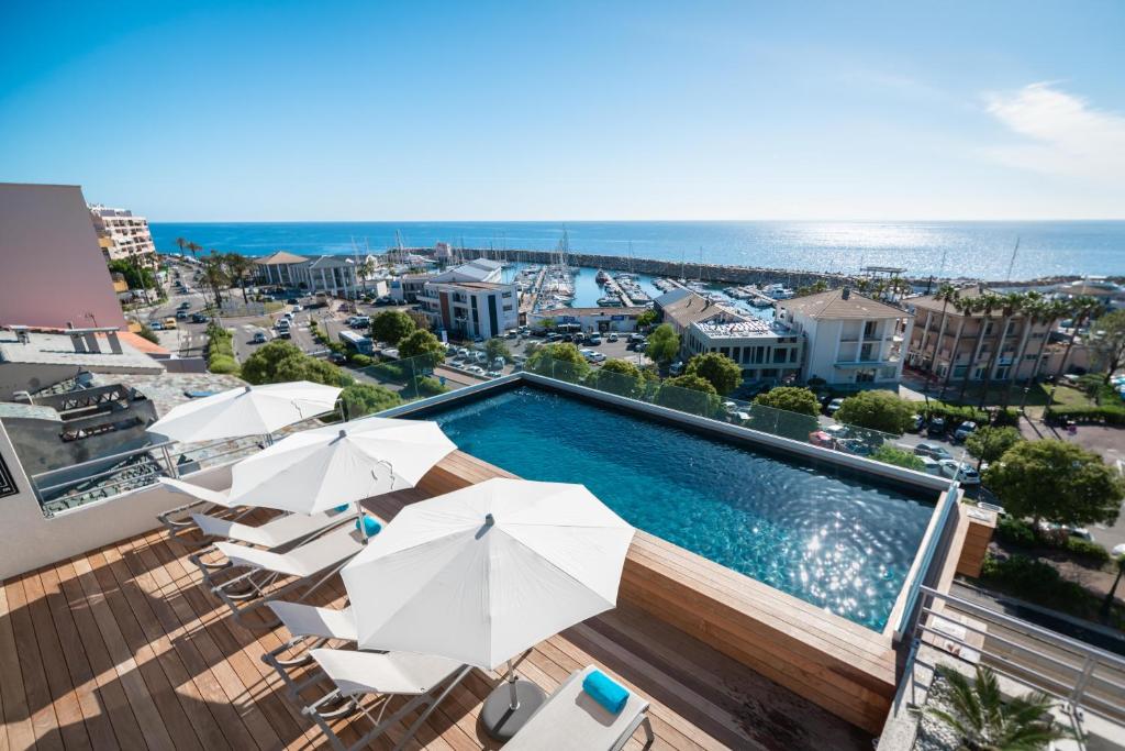 巴斯蒂亚托加港酒店的一个带遮阳伞和椅子的游泳池以及大海