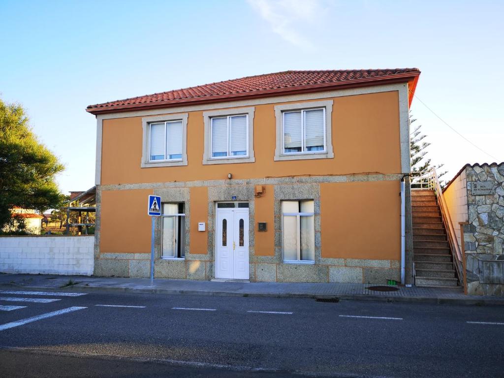 里贝拉Piso da Horta en Aguiño, Ribeira, Galicia的一条橙色的房子,街上有一道白色的门