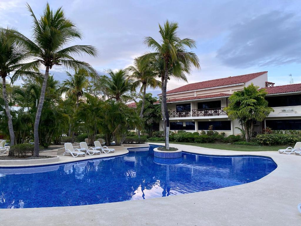 普拉亚科罗纳多Hermosa suite de playa, con vista al golf en Coronado的一个带椅子和棕榈树的游泳池的度假酒店