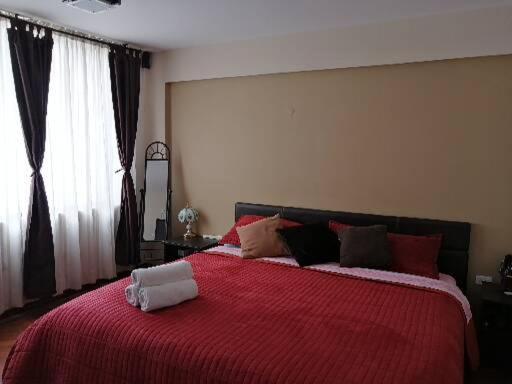 基多FAKALI Homestay的一间卧室配有一张带红色毯子的大床