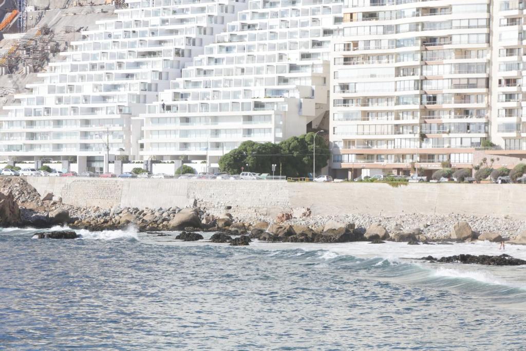 维纳德马Resetéate frente al Mar!! Disfruta en primera línea de Cochoa-Reñaca的海滩上的一群岩石,有一座大建筑