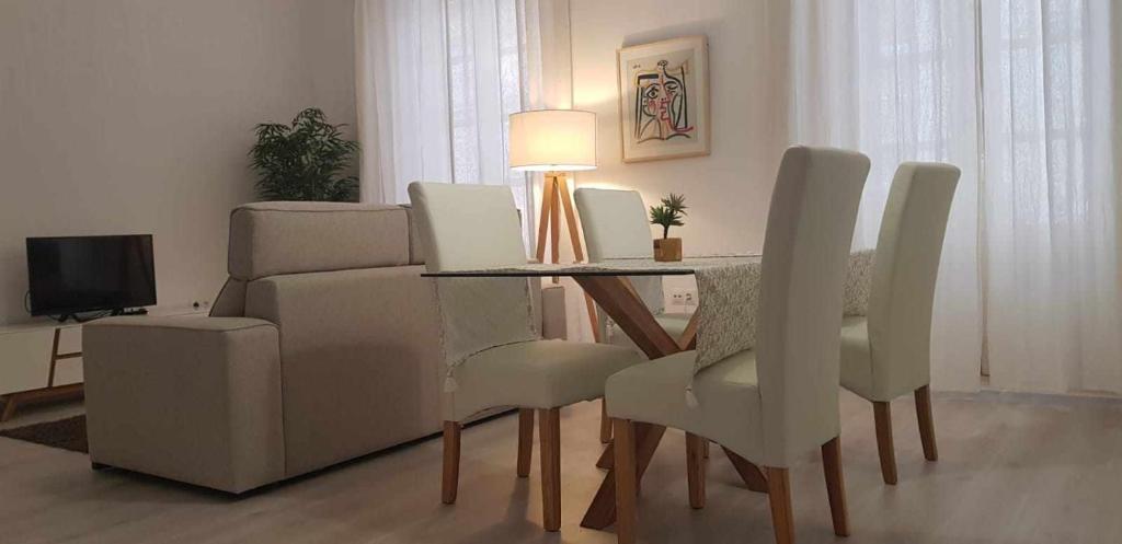 马拉加Acogedor Apartamento en el Corazón de Málaga的一间带桌椅和电视的用餐室