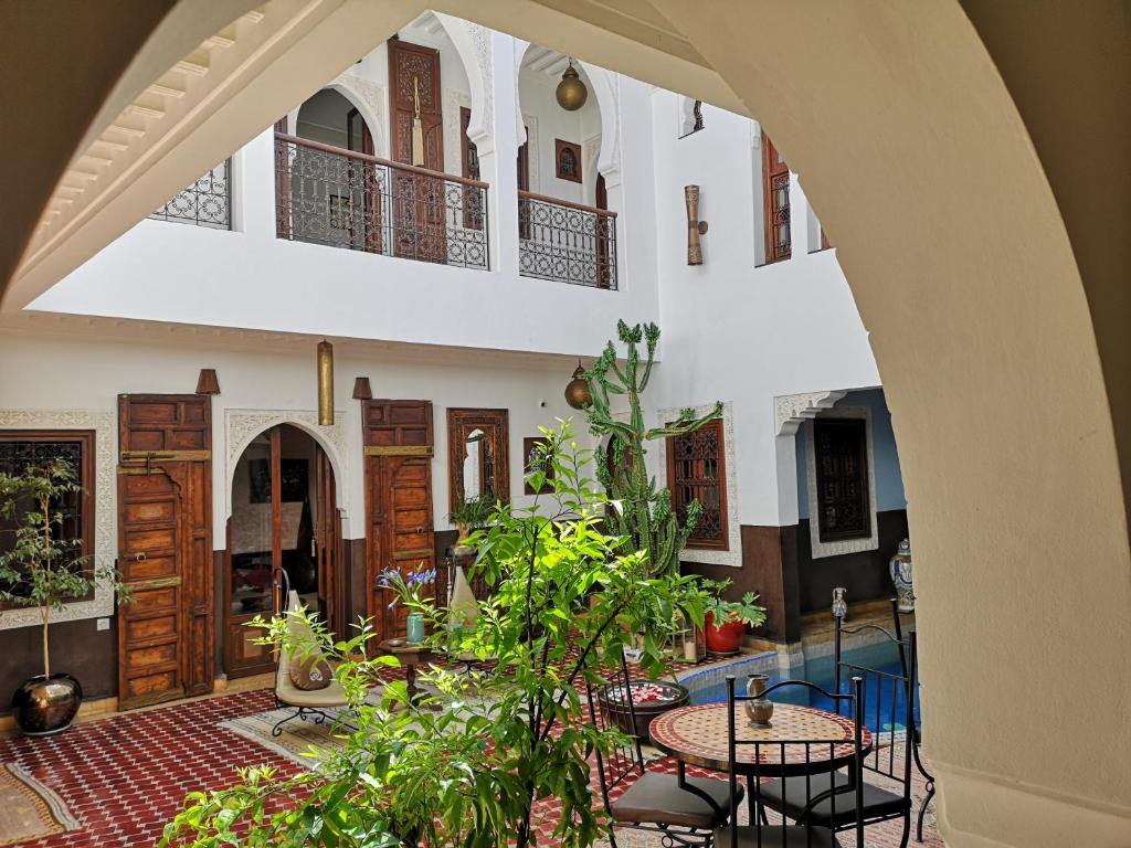 马拉喀什东方魅力摩洛哥住宅酒店 - 仅限成人的一座庭院,楼内种有桌子和植物