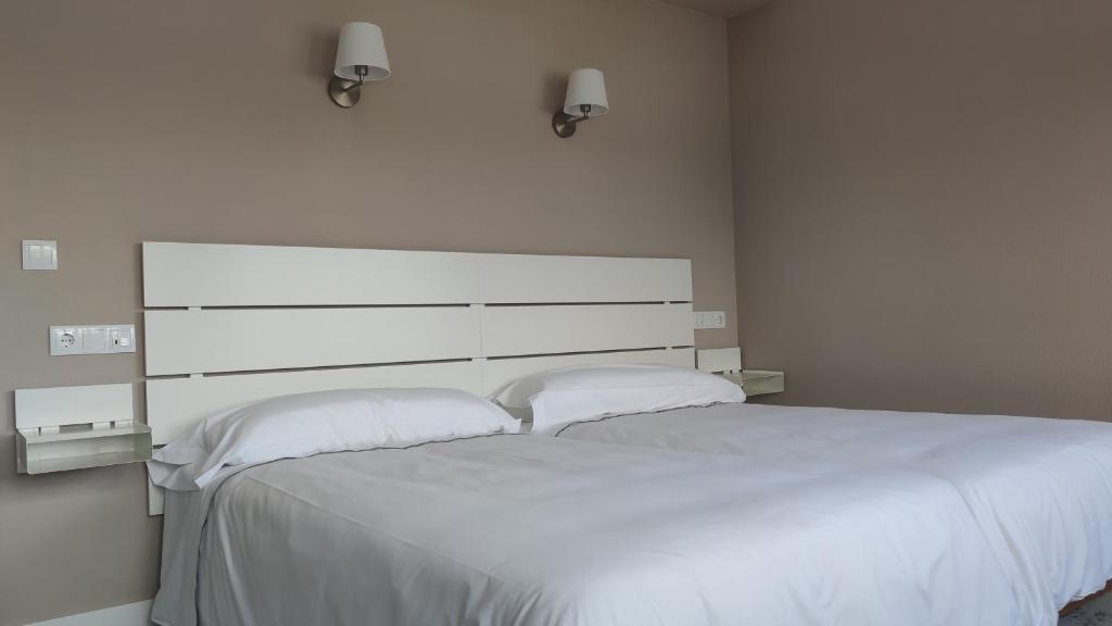 NavecesHotel Román的卧室配有一张带两个枕头的大白色床