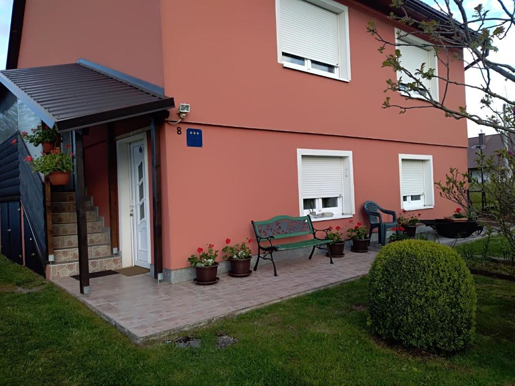 代尔尼采Apartman Ris Gorski Kotar Crni Lug的粉红色的房子,前面有长凳