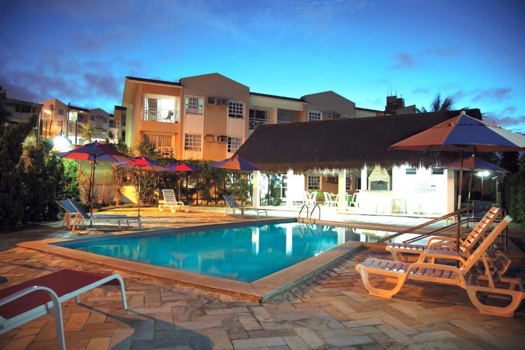 纳塔尔公寓村酒店的度假村内带椅子和遮阳伞的游泳池