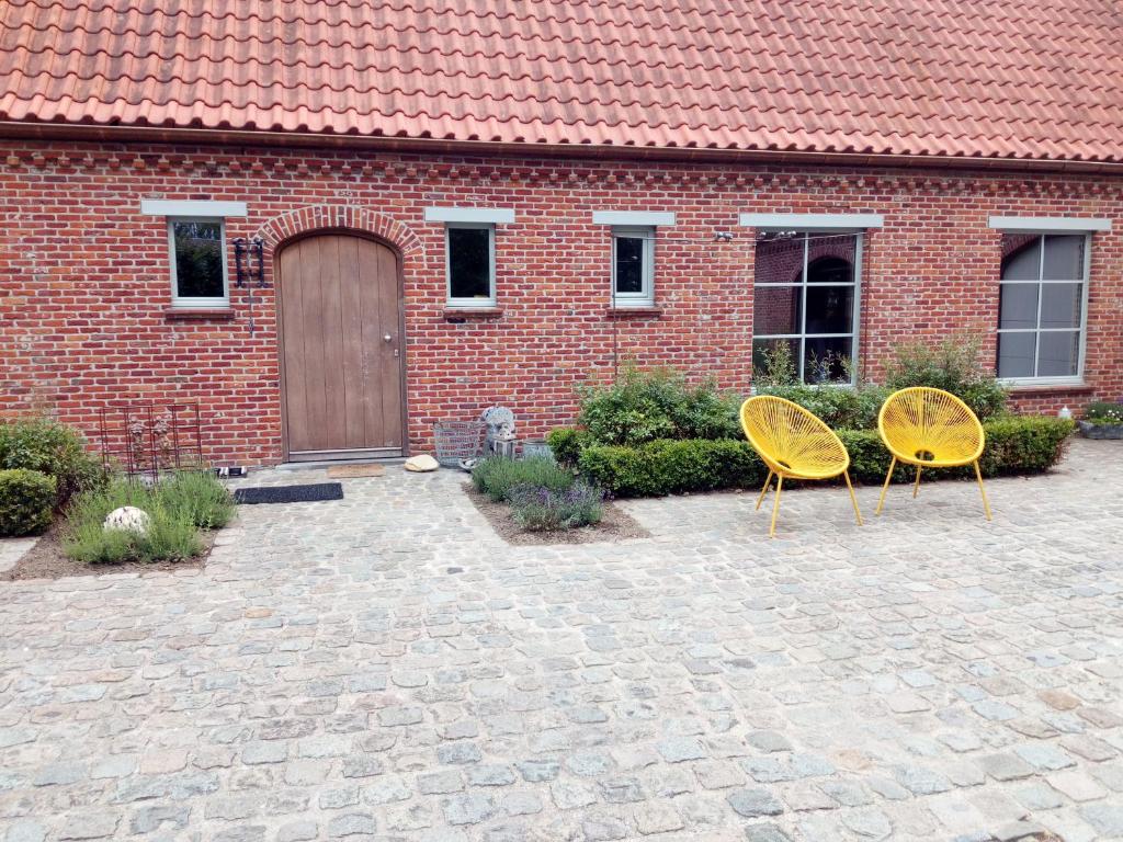 OedelemLetteratelier drieSprong的两把黄色椅子坐在砖楼前