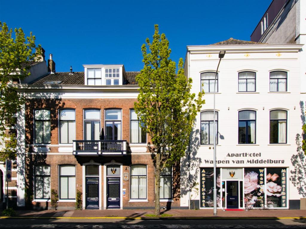 米德尔堡ApartHotel Waepen van Middelburg的前面有棵树的白色建筑