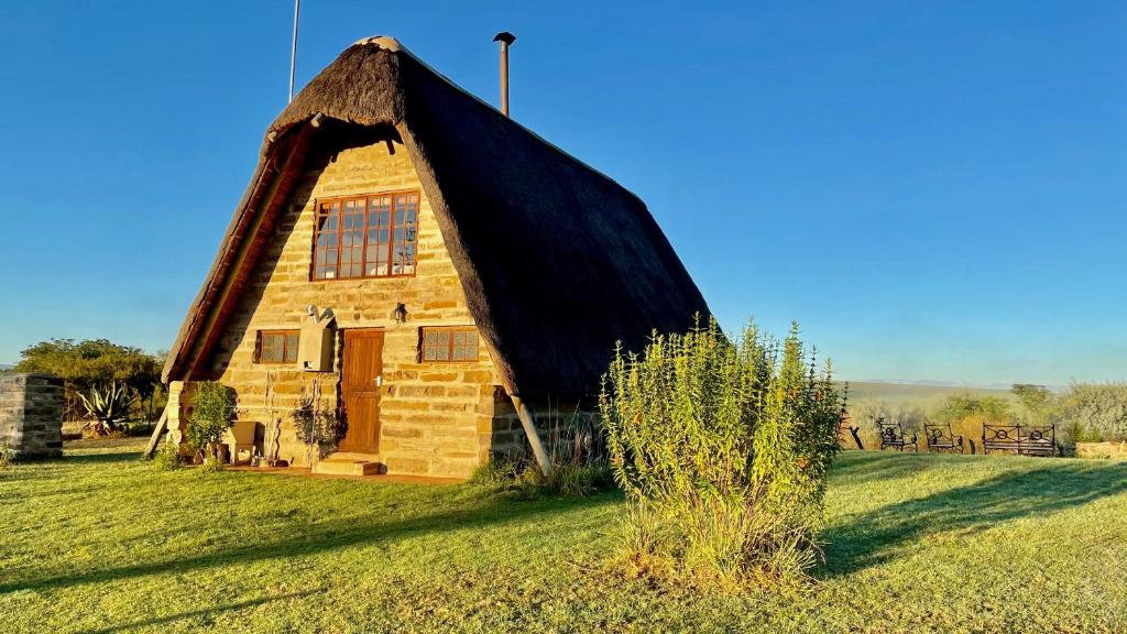 温特顿Tugela River Lodge的田野上茅草屋顶的房子