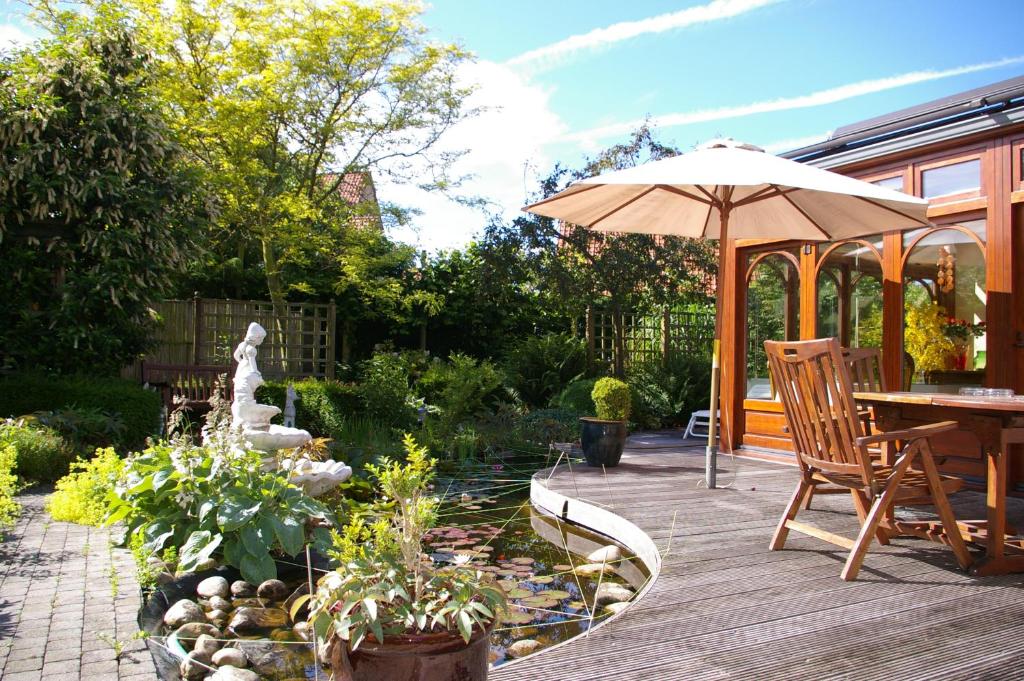 科克赛德B&B VILLA MONIQUE的庭院配有遮阳伞和桌椅。
