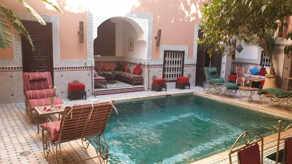 马拉喀什里亚德巴洛克旅馆的一个带椅子和沙发的房子内的游泳池
