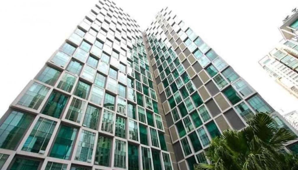 吉隆坡Soho Suites KLCC By iRent365的一座高大的玻璃建筑,前面有棕榈树