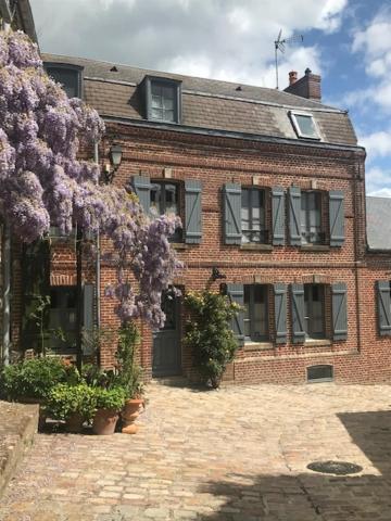 索姆河畔的圣瓦列里Chambres avec Vue的一座大砖砌建筑,上面有紫色的花