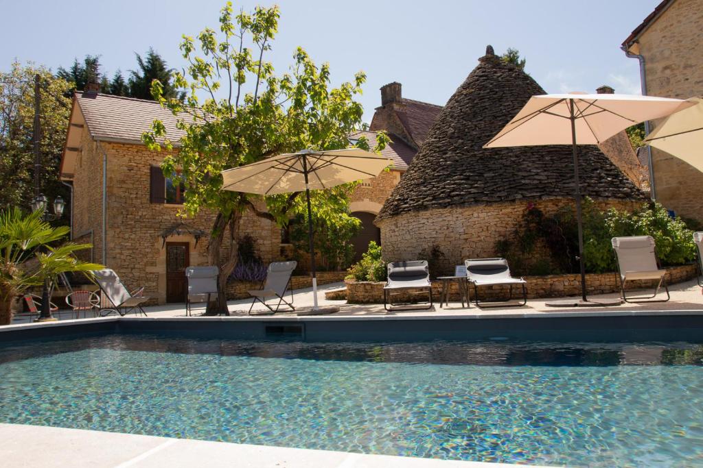 马尔凯Le Four à Pain, Gîte avec piscine et SPA proche Sarlat的房屋旁的游泳池配有椅子和遮阳伞