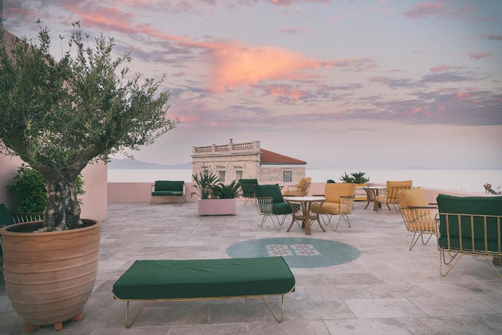 埃尔莫波利斯Aristide Hotel - Small Luxury Hotels of the World的一个带桌椅的庭院和天空画