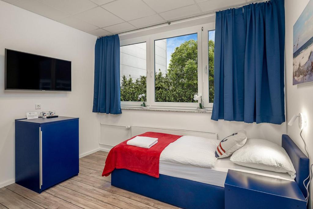 汉堡Koje Hostel的一间卧室配有一张带蓝色窗帘的床和电视。