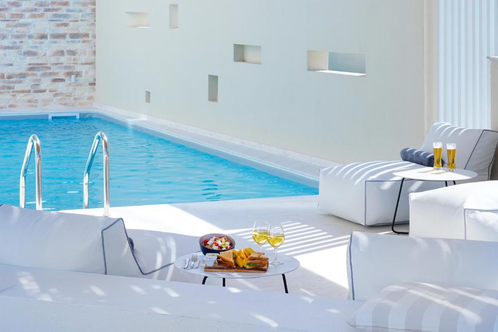 萨索斯阿利亚别墅的一个带白色家具和酒杯桌子的游泳池