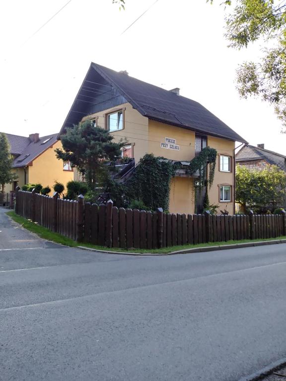 ŻabnicaNoclegi Przy Szlaku Agroturystyka的街道边有围栏的黄色房子