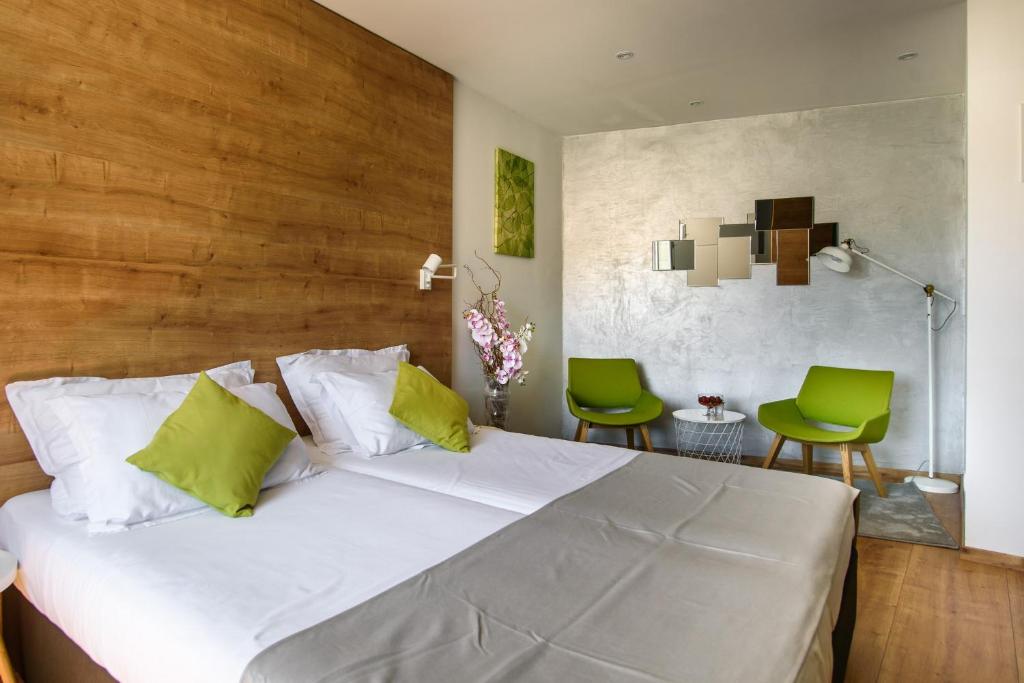 杜布罗夫尼克Ora Luxury Rooms的一间卧室配有白色的床和两张绿色椅子