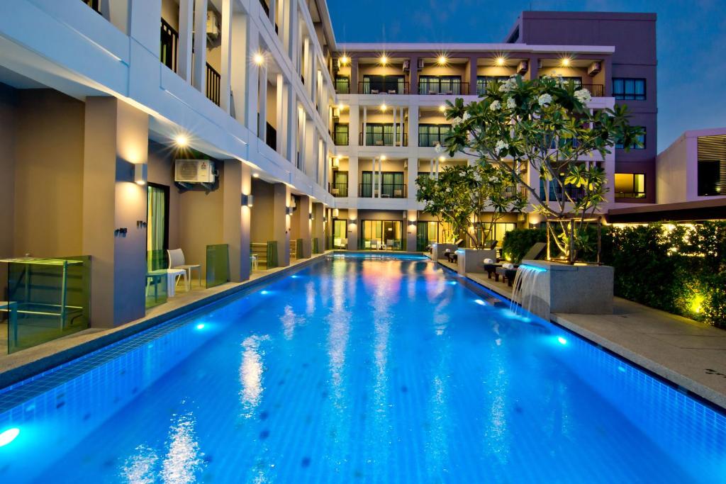 芭堤雅市中心Hotel J Residence Pattaya - SHA Extra Plus的一座游泳池,在晚上在建筑物前