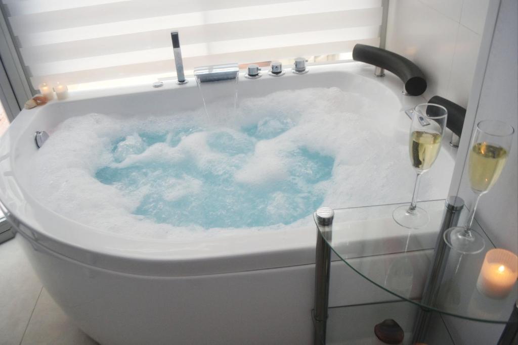 内尔哈Blue Horizon Luxury Apartment的配有蓝水和酒杯的浴缸