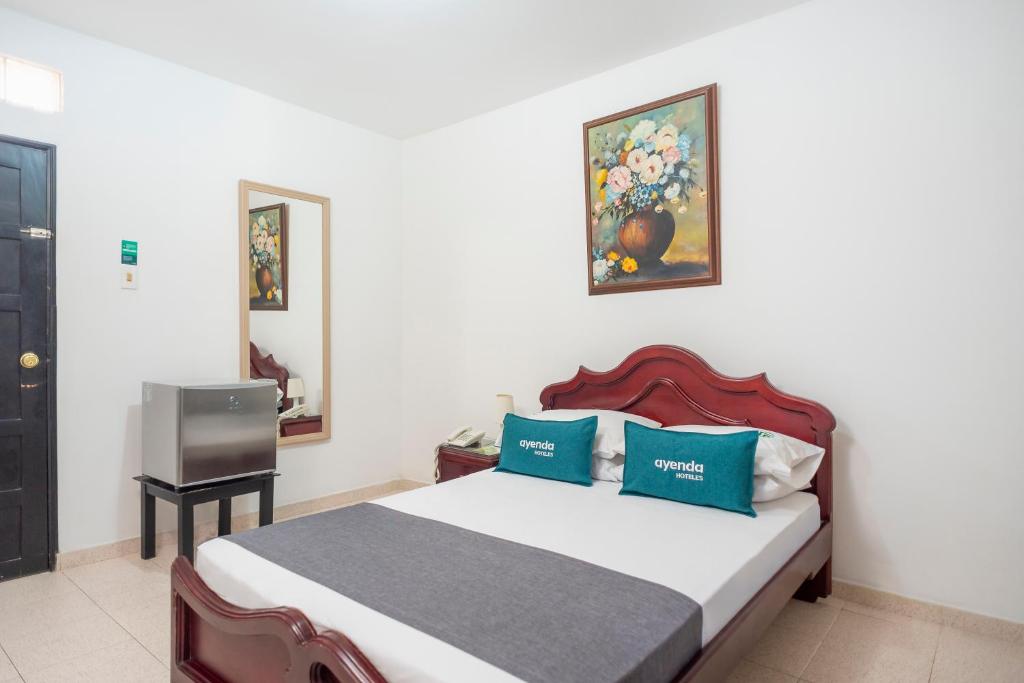巴兰基亚Ayenda 1309 Villa Dilia的一间卧室配有一张带蓝色枕头的床和一台电视。