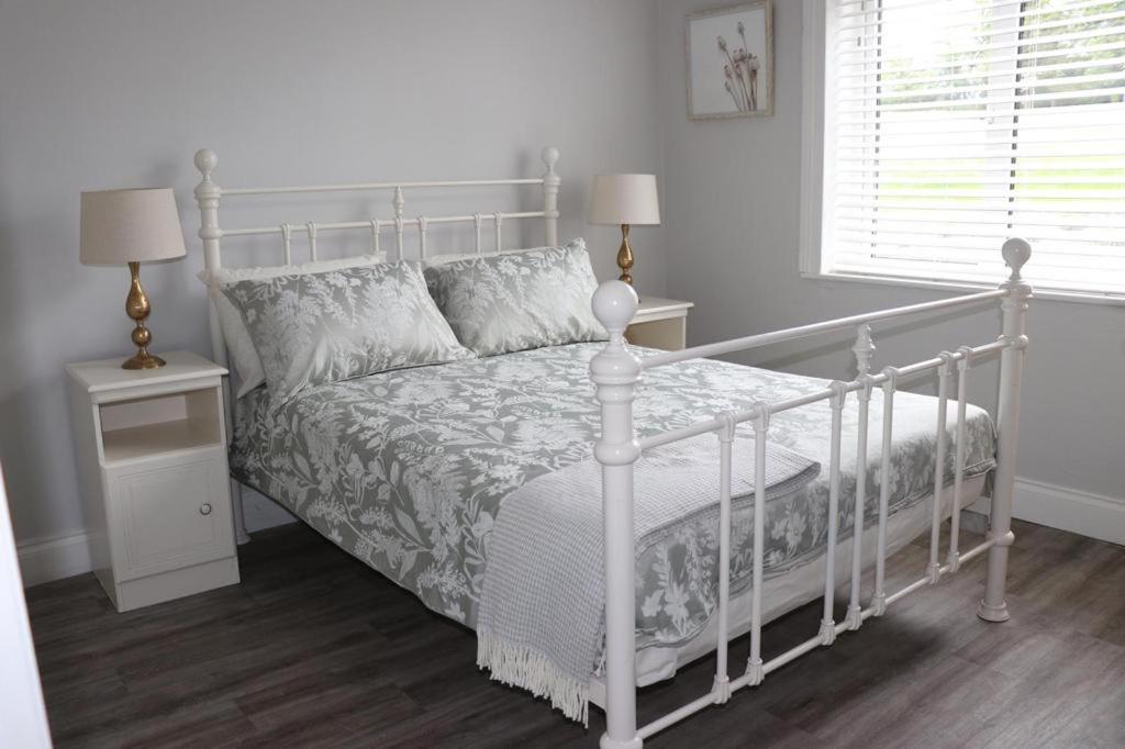 基拉尼WILLOW COUNTRY COTTAGE的白色卧室内的一张白色床,设有2个床头柜