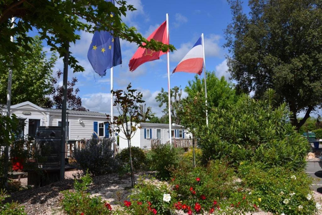 图卢兹CAMPING LE RUPE的白房子前面的三面旗