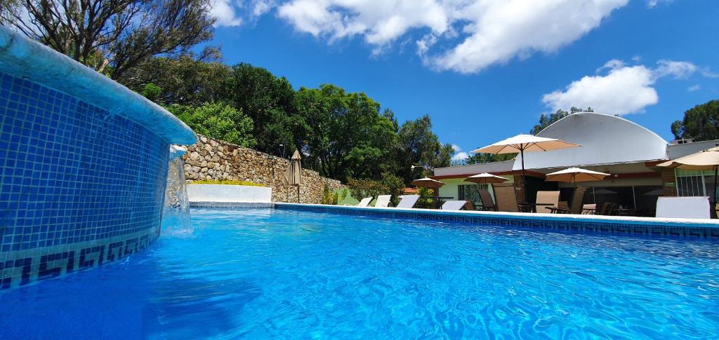 伊斯塔潘德拉萨尔Victoria Hotel y Spa的一个带椅子和遮阳伞的蓝色游泳池