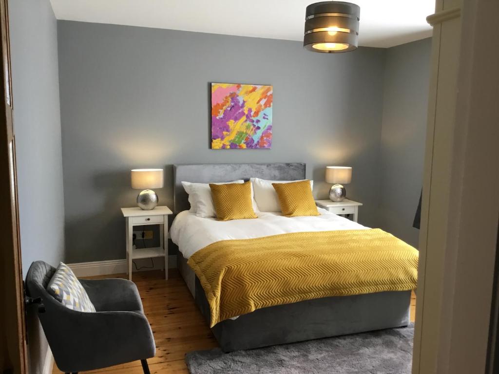 杜林Knockaguilla House Bed & Breakfast的一间卧室配有一张带黄色枕头和椅子的床