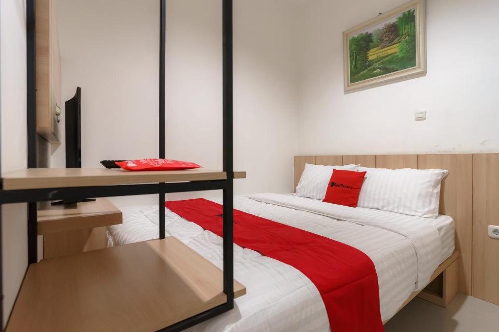 雅加达RedDoorz near Seasons City Mall 3的一间卧室配有一张带书桌和红毯的床。