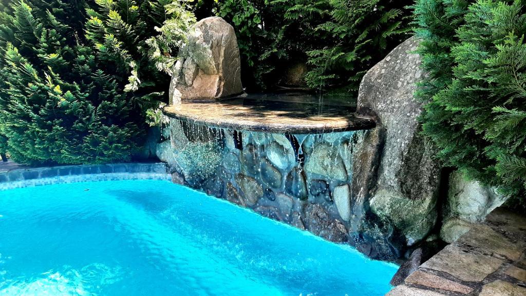 Shtarkelovo GnezdoVilla Anna Luxury Lake Residence的一座游泳池,其瀑布位于石墙旁