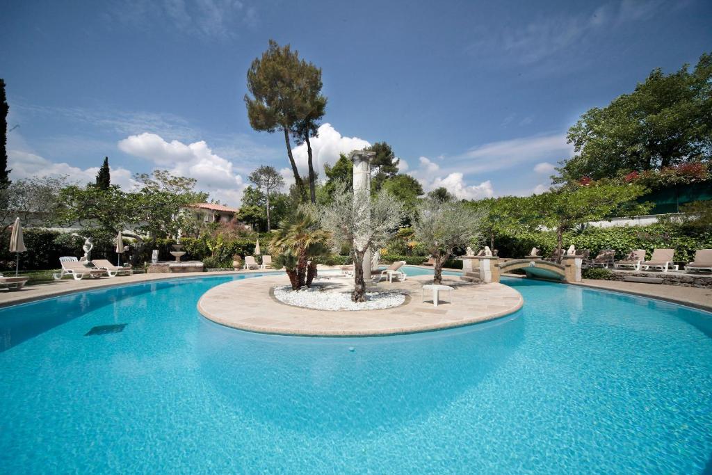 圣保罗-德旺斯Hotel Les Messugues的中间有一个种有树的大型游泳池